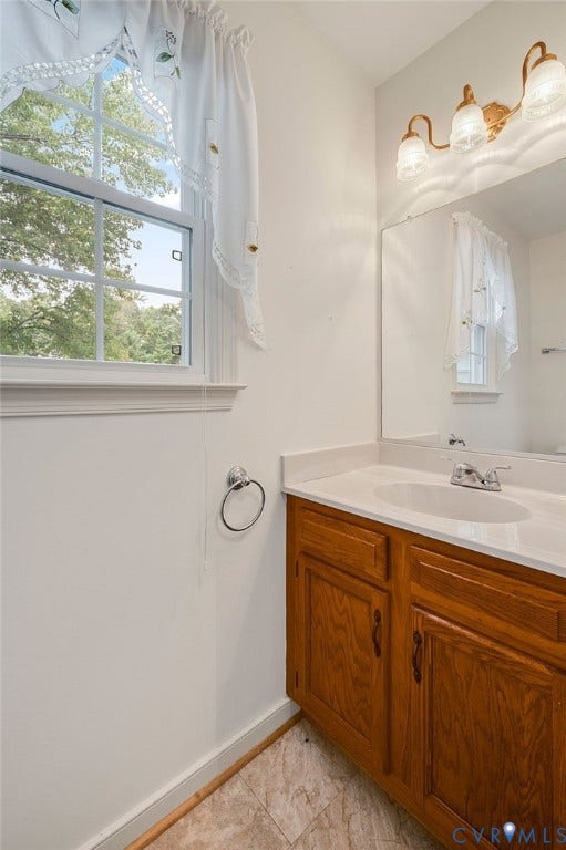 3005 Wiltonshire Drive, Richmond, VA 23233 White-framed window, bright vanity lighting, built-in wooden vanity with cabinet storage, integrated sink, and a large wall-mounted mirror