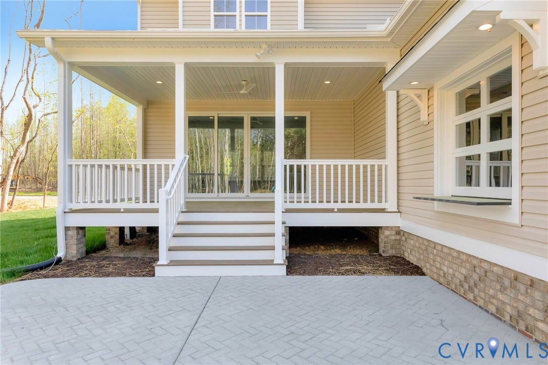 The property features a covered porch with white railings and recessed lighting, accessible via stairs