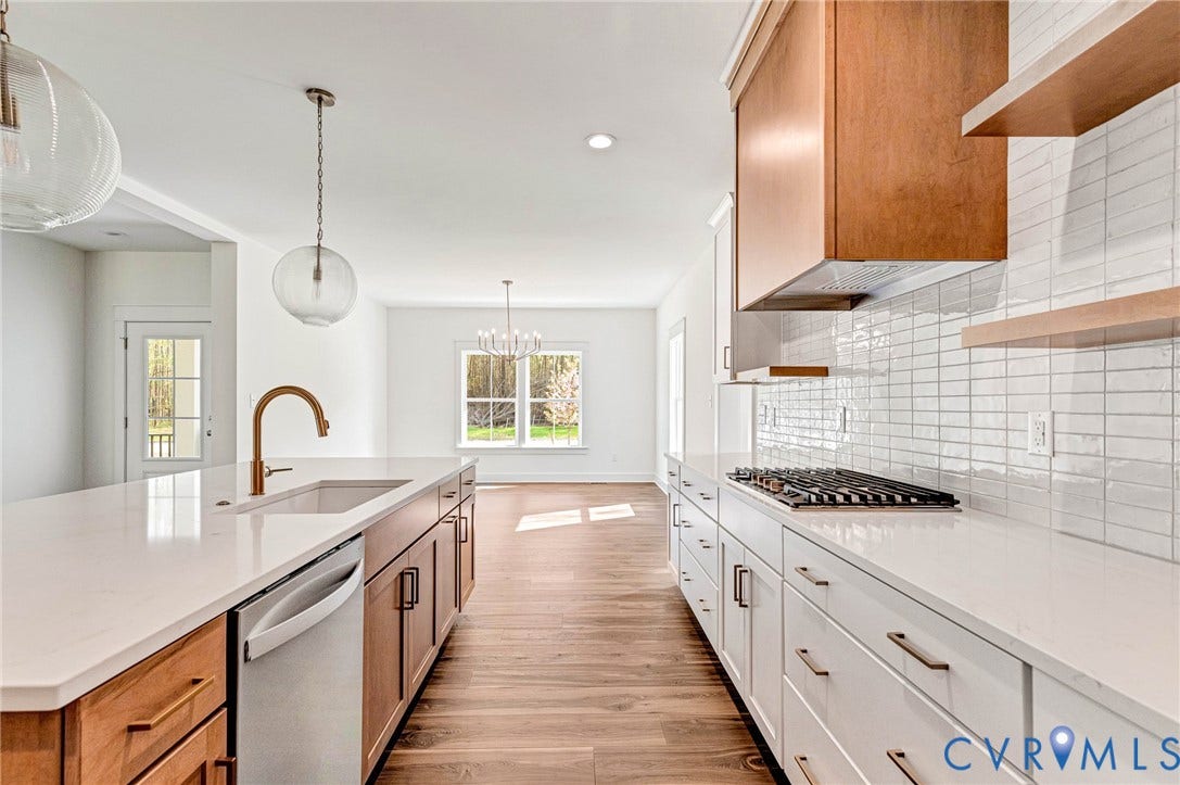 The kitchen features a gas cooktop, white subway tile backsplash, and light wood flooring