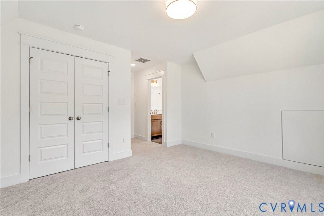 This bright room features neutral carpeting, a ceiling-mounted light fixture, and white bi-fold closet doors