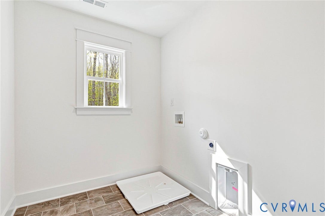 Utility room with a window providing natural light, white walls, and tiled flooring