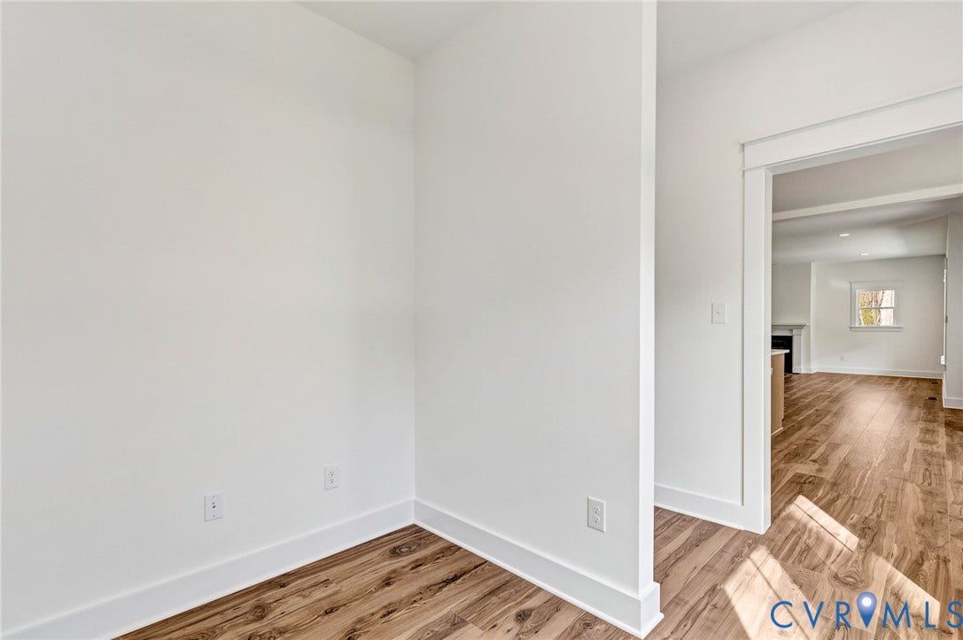 This interior space features hardwood style flooring, white walls, and white trim