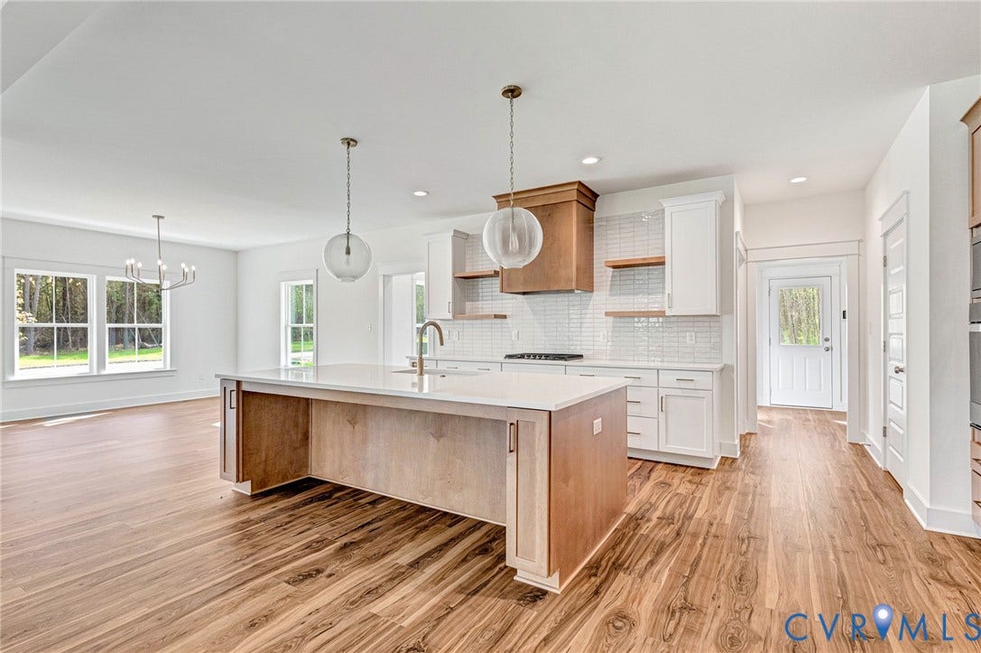 The property features an open-concept kitchen with a large island, white cabinetry, and a subway tile backsplash