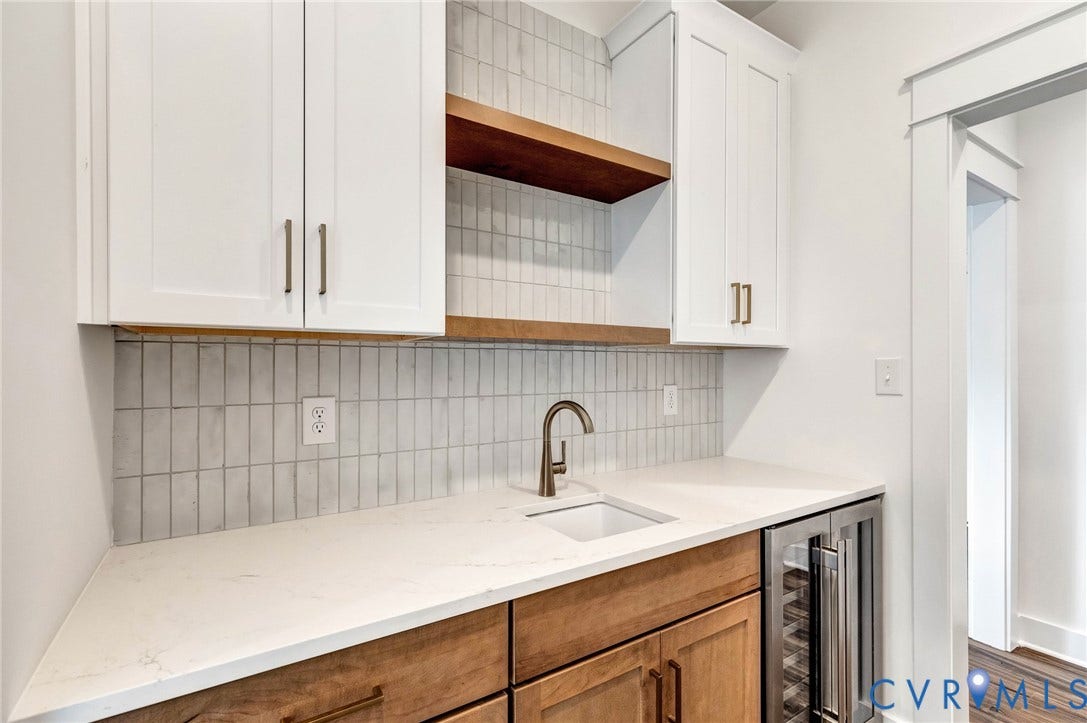 The property features a built-in bar area with white upper cabinetry, a wood shelf, and wood lower cabinetry