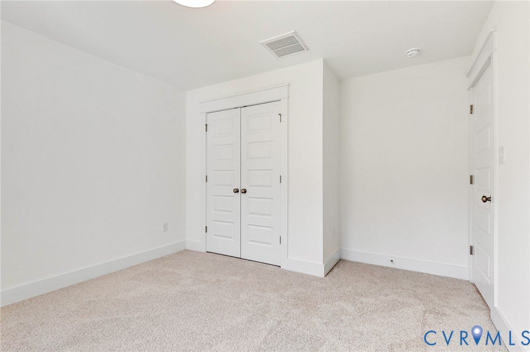This room features neutral-toned carpeting and pristine white walls, offering a versatile canvas for personalization
