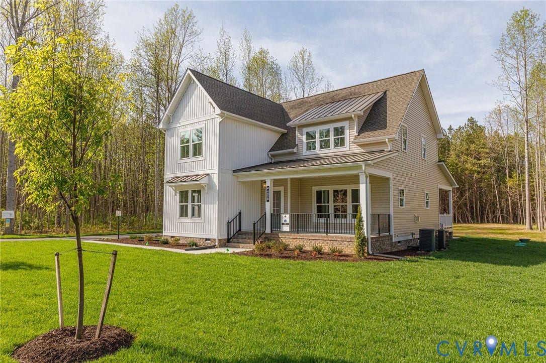 This property features a two-story exterior with a combination of light-colored siding, a covered front porch with dark railings, and a well-maintained lawn