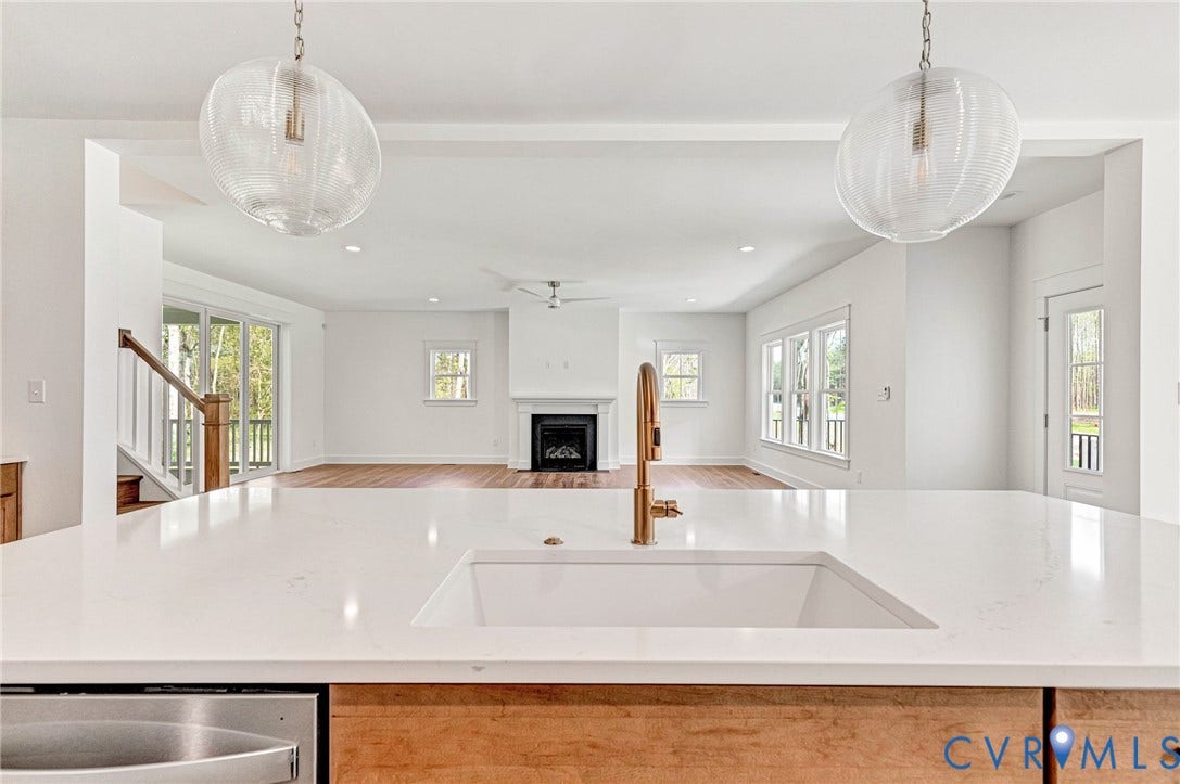 The kitchen features a large island with a white countertop and an integrated sink with a gold-toned faucet