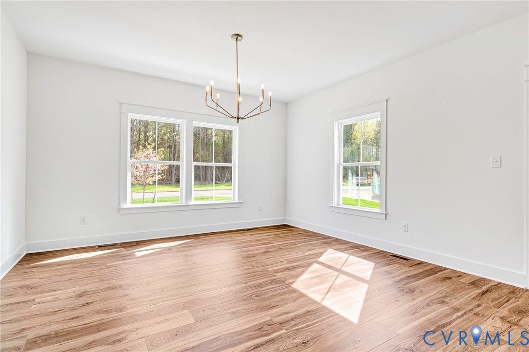 This room features light-colored walls, wood flooring, and a modern chandelier
