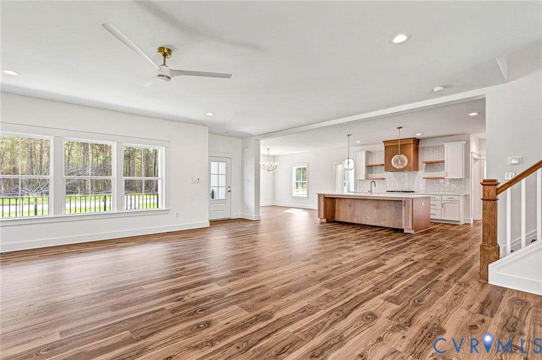 This spacious open-concept interior features wood flooring and a modern ceiling fan with a gold-tone fixture