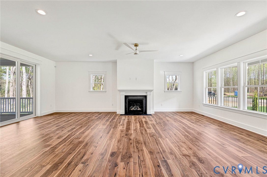 Spacious living area featuring hardwood flooring, a fireplace with a mantel, recessed lighting, and a ceiling fan