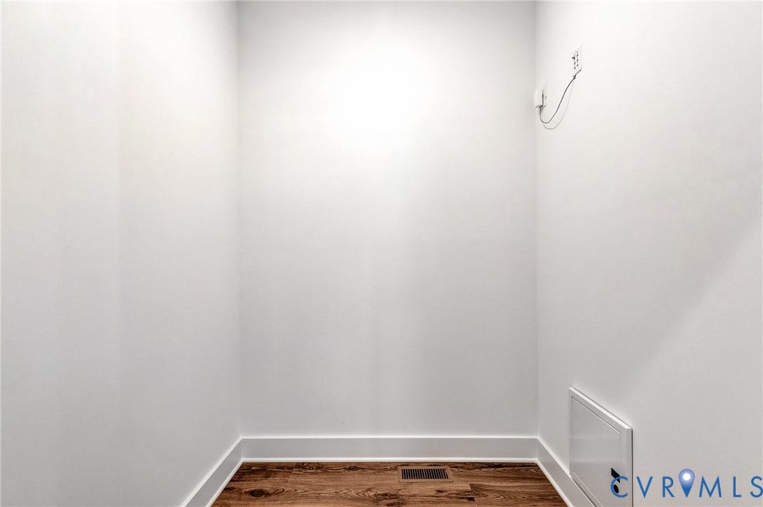 This space features white walls, dark wood flooring, and white trim