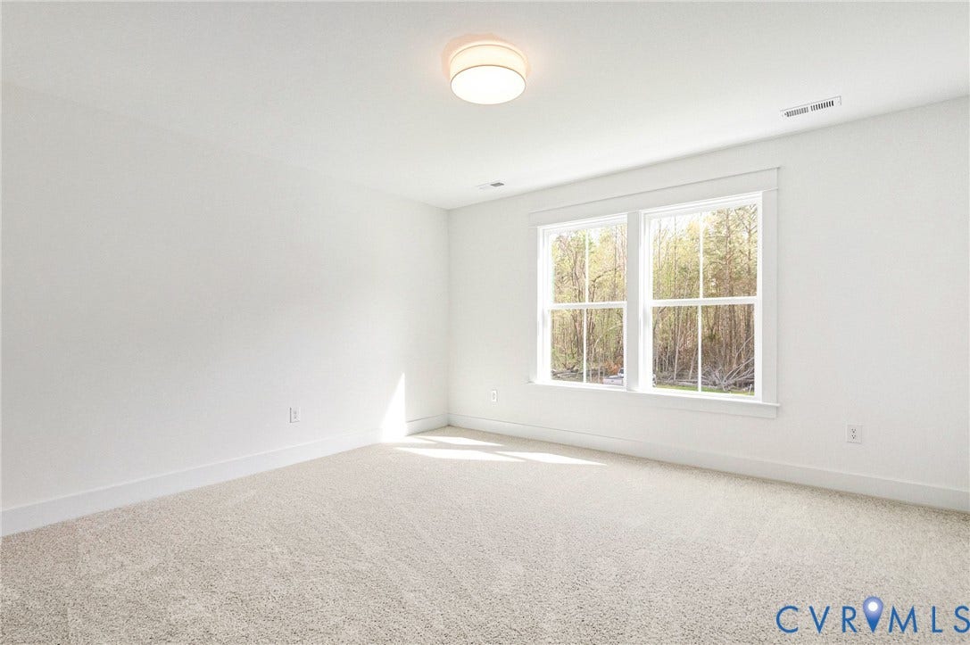 This bright room features a neutral carpet, white walls, and a contemporary ceiling light fixture