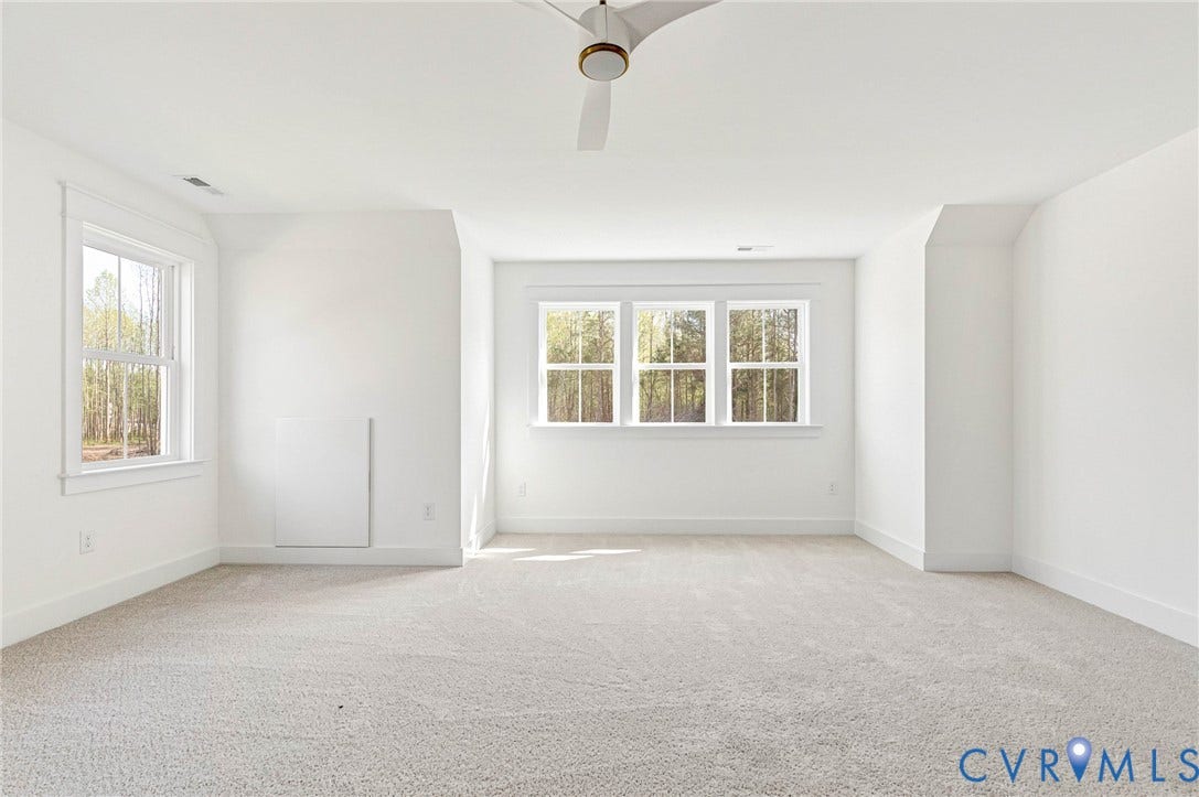 This versatile room features light-colored carpeting, white walls, and multiple windows that provide natural light