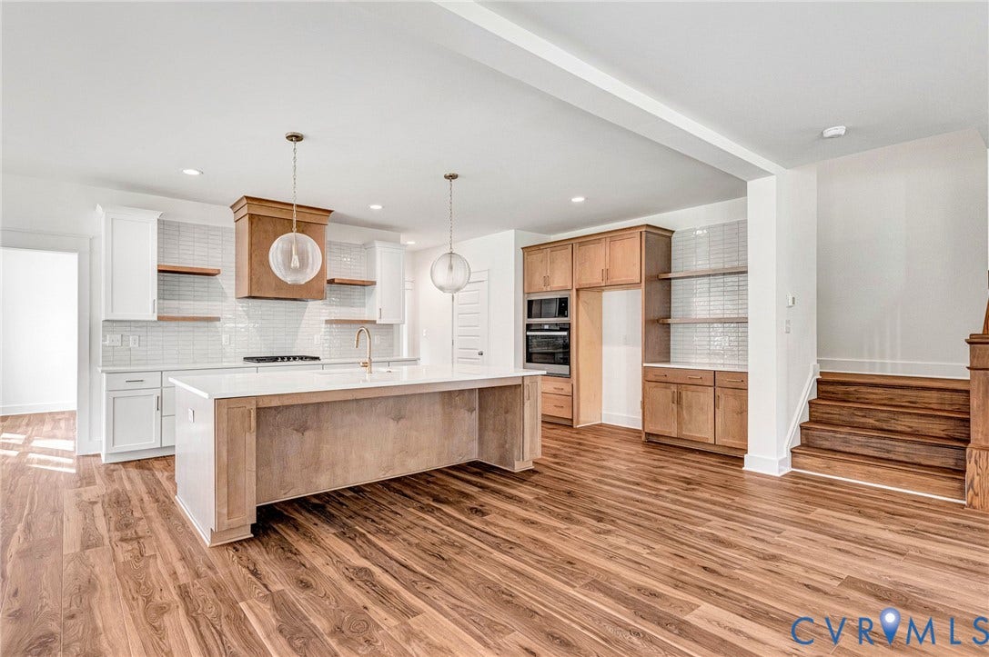 The property features hardwood floors, a kitchen island with a white countertop, and white kitchen cabinetry