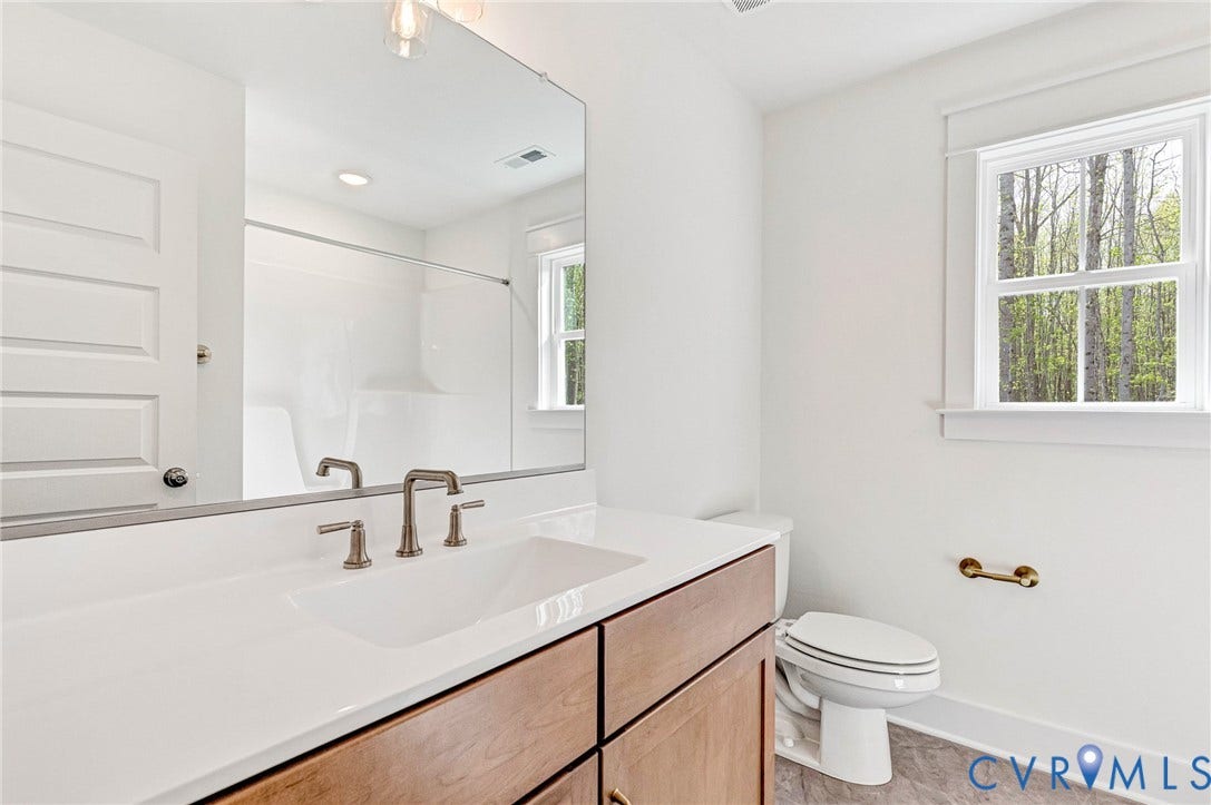 The bathroom features a vanity with a white countertop and a rectangular sink, set against white walls