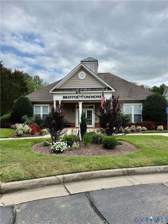 Community building entrance with shrubbery, and a manicured lawn