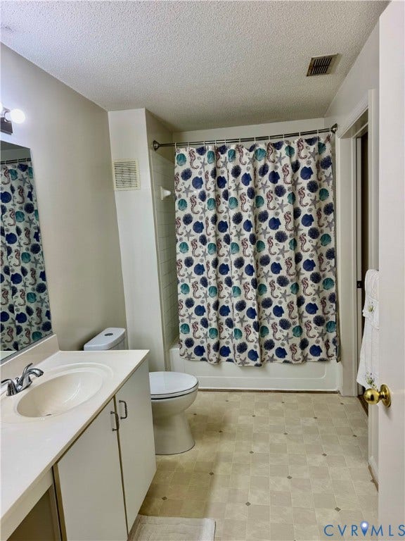 Bathroom featuring a built-in tub with shower, single vanity with integrated sink, and a toilet