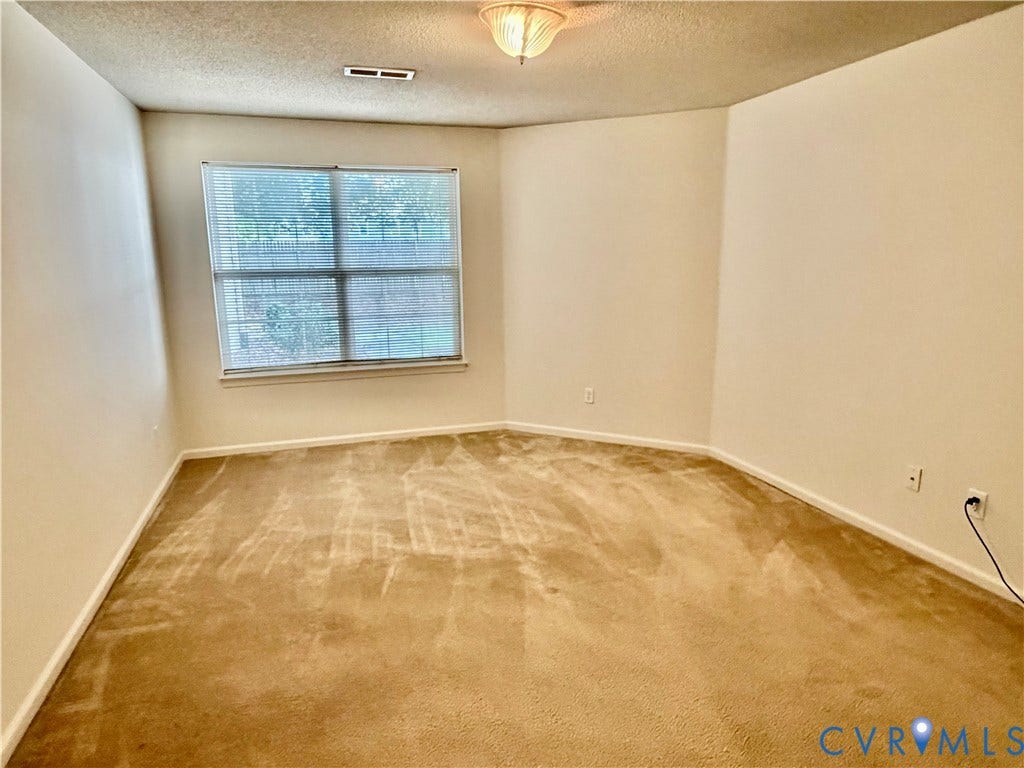Neutral tone wall finishes, wall-to-wall carpeting, and a window with horizontal blinds