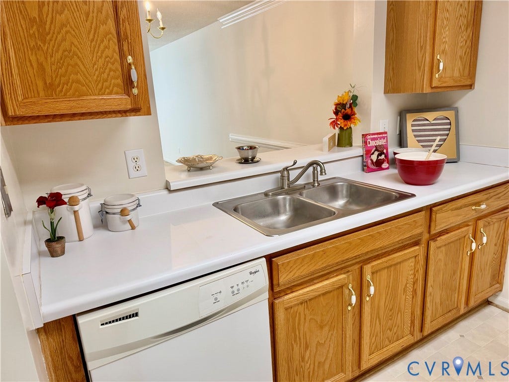Kitchen featuring wood-finish cabinetry, white countertops, a double basin stainless steel sink, and a built-in dishwasher