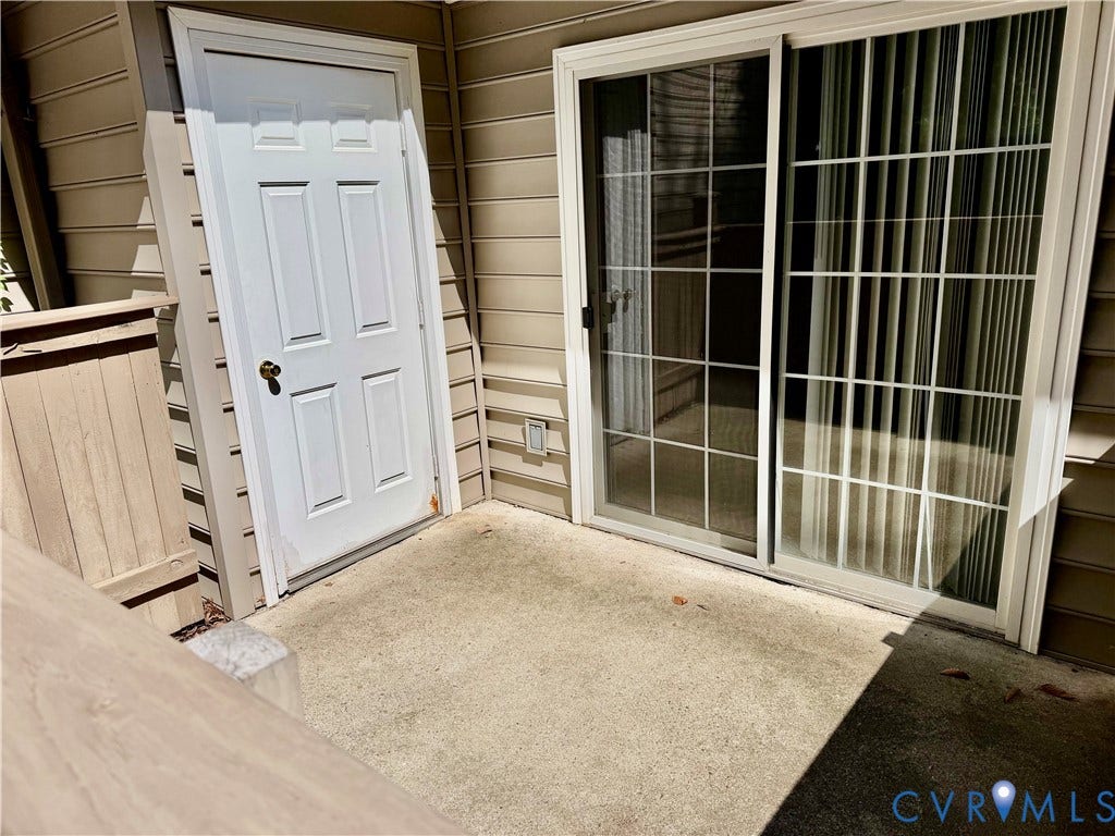 Private concrete patio with a paneled exterior door to the storage closet and a sliding glass door from the living room