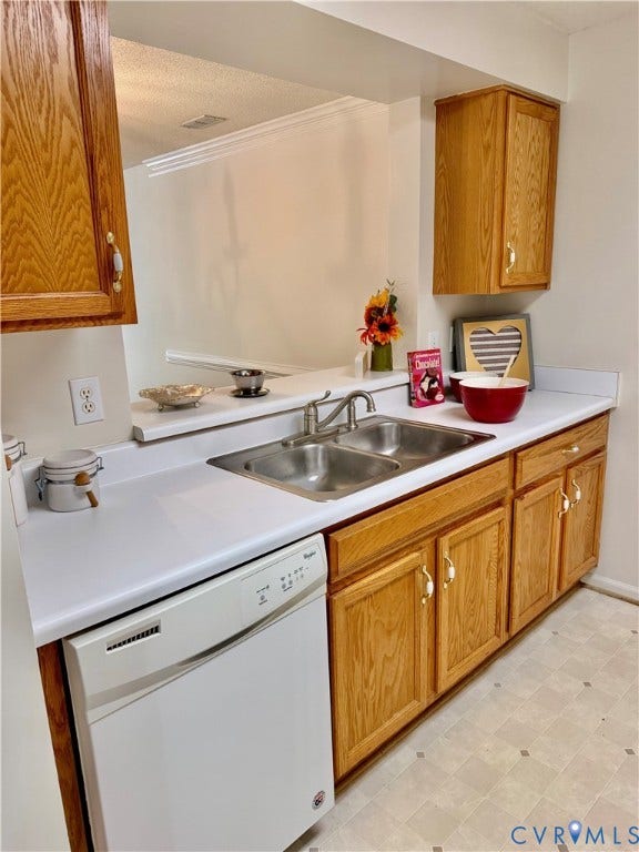 Wood-finish cabinetry, white countertops, double basin sink, and a built-in dishwasher