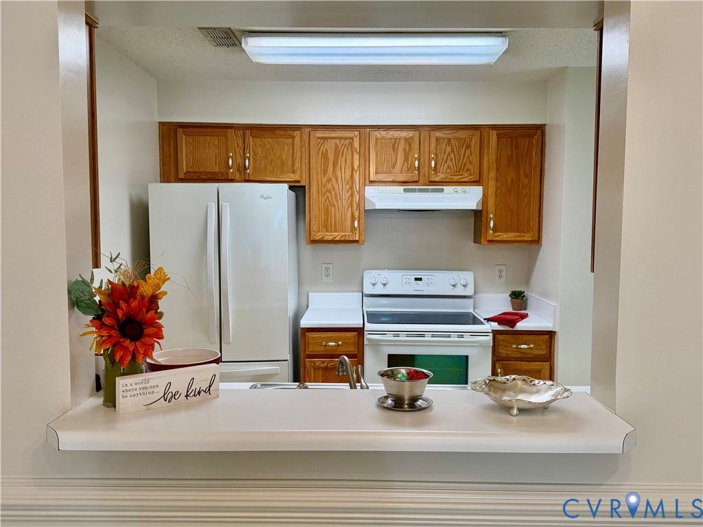 Kitchen featuring wood-finish cabinetry, white appliances, and a breakfast bar