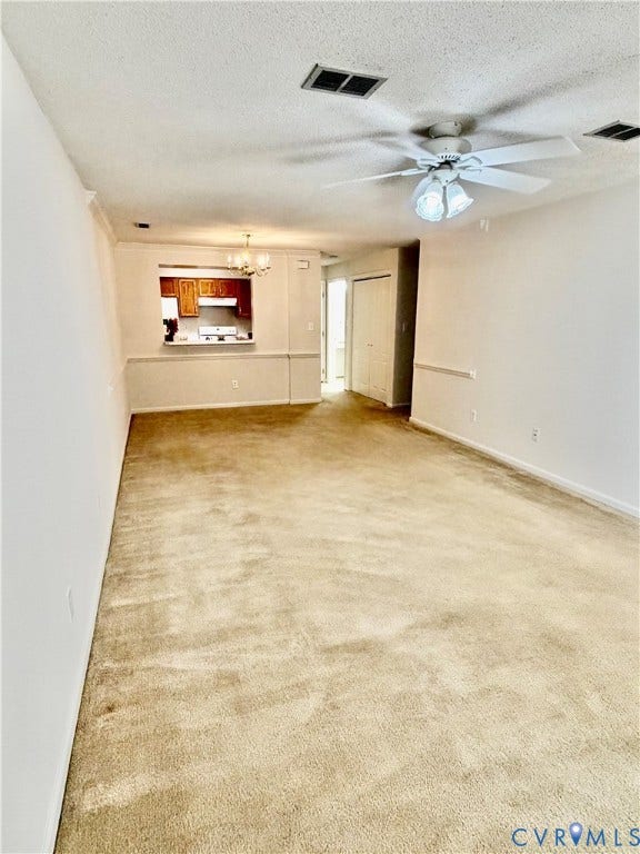 Spacious room with neutral carpeting and a ceiling fan