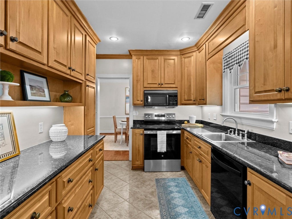 216 Ross Road, Westham Area, Henrico, VA 23229 Wood cabinetry with dark hardware, dark countertops, tiled flooring, stainless steel range and microwave, and a stainless steel double basin sink