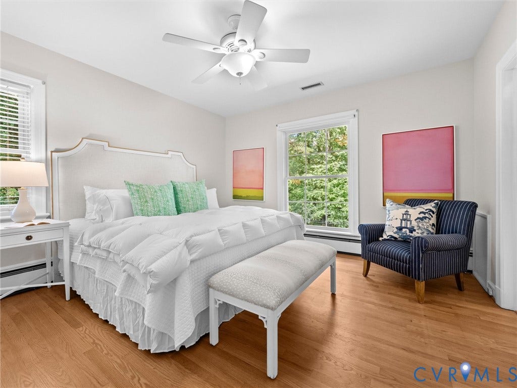 216 Ross Road, Westham Area, Henrico, VA 23229 Bright, light-filled bedroom showcasing hardwood flooring, a ceiling fan with integrated lighting, and large windows framing natural greenery