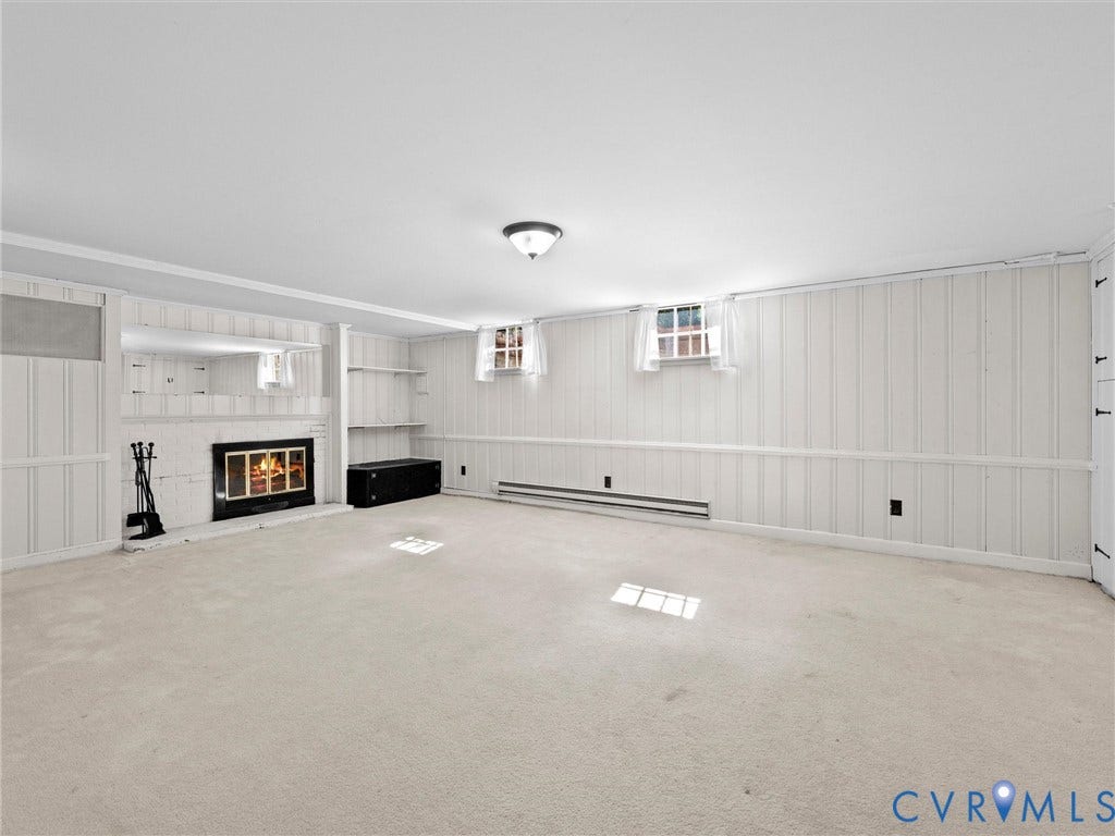 216 Ross Road, Westham Area, Henrico, VA 23229 Spacious room featuring a fireplace with a black surround, white board and batten paneling, built-in shelving, and carpet flooring