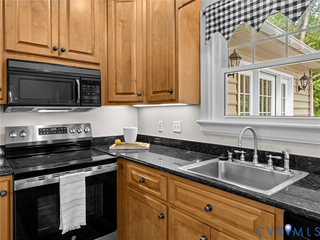 216 Ross Road, Westham Area, Henrico, VA 23229 Warm wood cabinetry with oil-rubbed bronze hardware pairs with a dark stone countertop and stainless steel sink, creating a classic kitchen aesthetic
