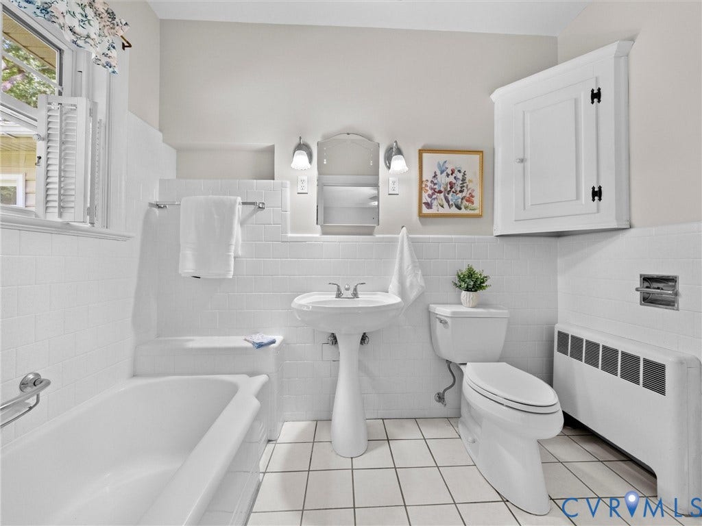 216 Ross Road, Westham Area, Henrico, VA 23229 Classic bathroom featuring a pedestal sink with chrome fixtures, subway tile walls, ceramic tile flooring, a soaking tub with surround, toilet, and white cabinetry with hardware accents