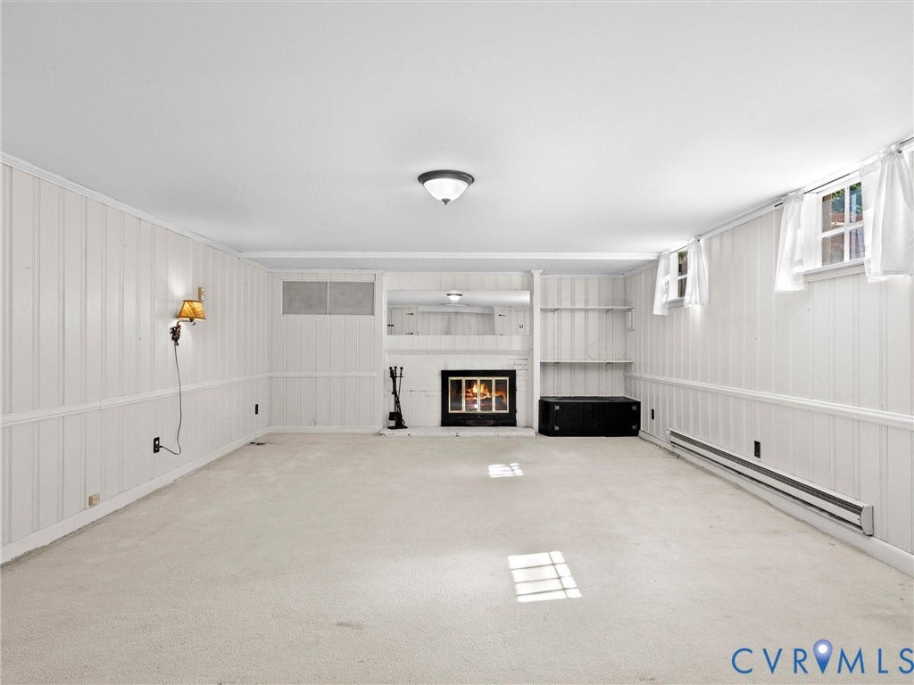 216 Ross Road, Westham Area, Henrico, VA 23229 Carpeted room with white paneling, featuring a white brick fireplace with a dark firebox, built-in shelving, and multiple windows