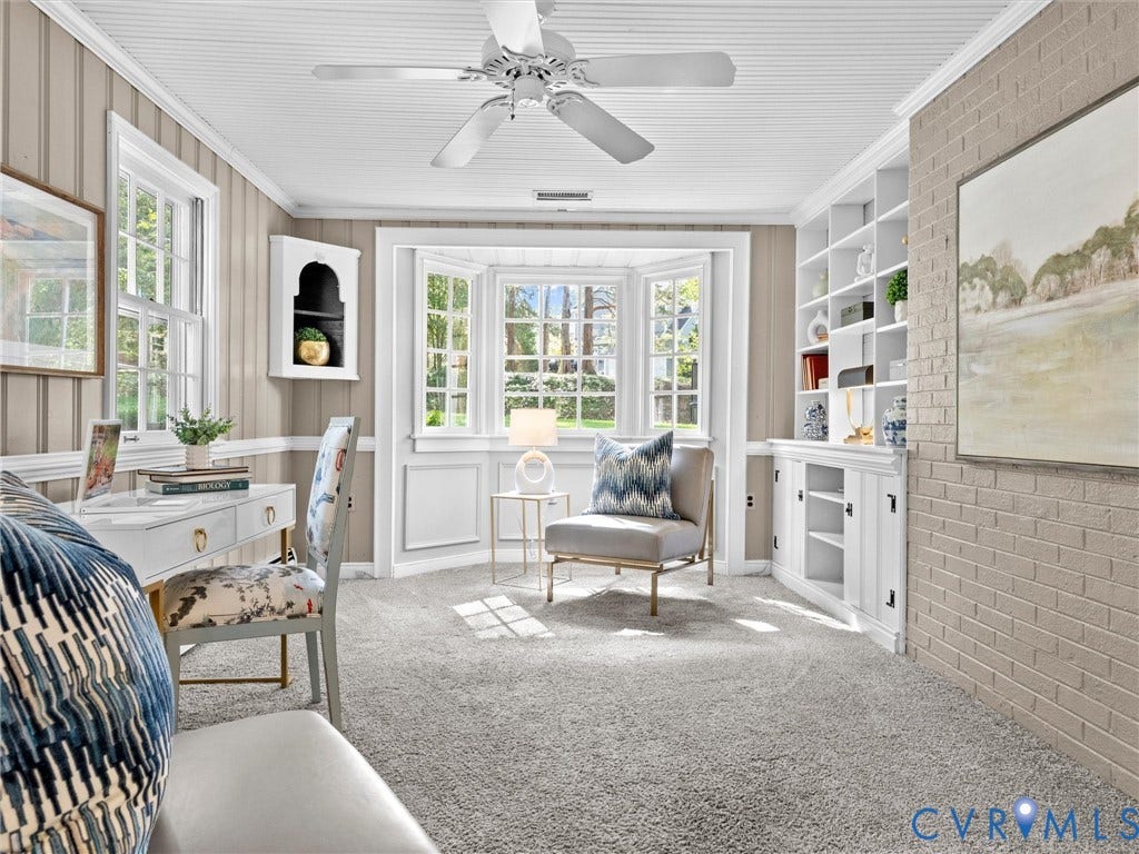 216 Ross Road, Westham Area, Henrico, VA 23229 Built-in shelving with lower cabinetry, bay windows, textured wall paneling, painted brick accent wall, and a ceiling fan with light fixture