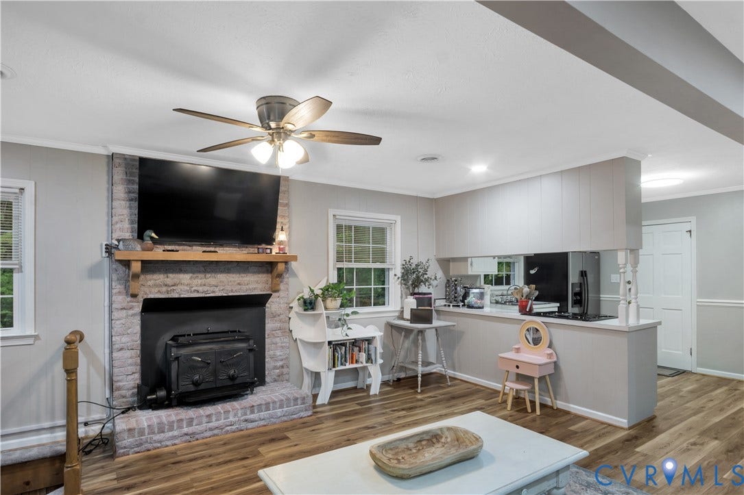 Wood-finish flooring, brick fireplace surround with a wood mantle, ceiling fan with integrated lighting, and recessed ceiling lighting