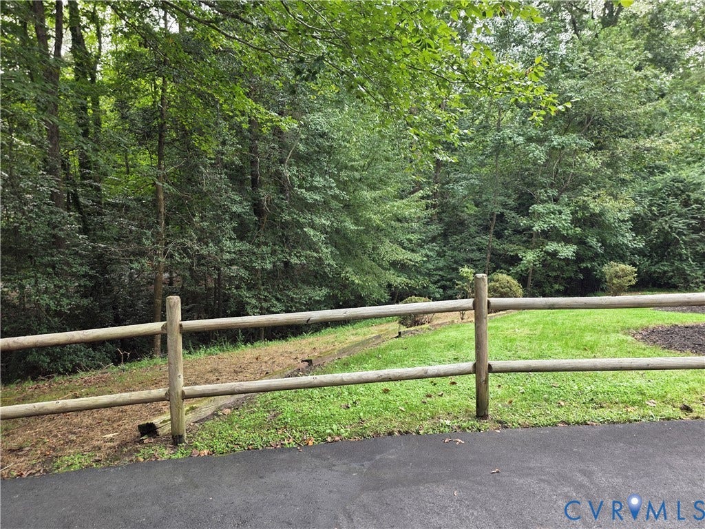 Split rail fence with abundant mature trees and a manicured lawn