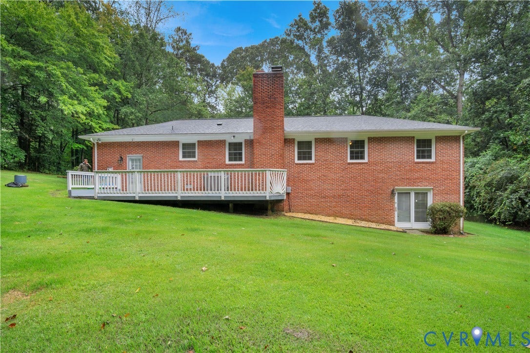 Brick exterior featuring a multi-level deck, a prominent brick chimney, and a lower-level glass sliding door