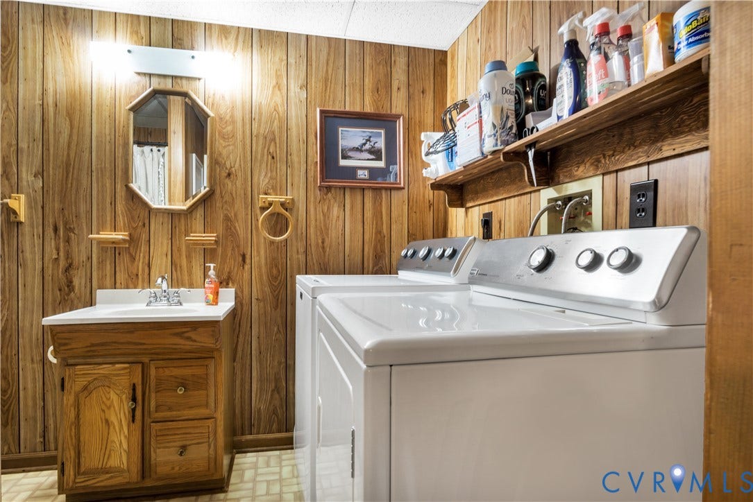 Wood-paneled room featuring a white vanity with a single basin, an octagonal mirror, and a wall-mounted light fixture