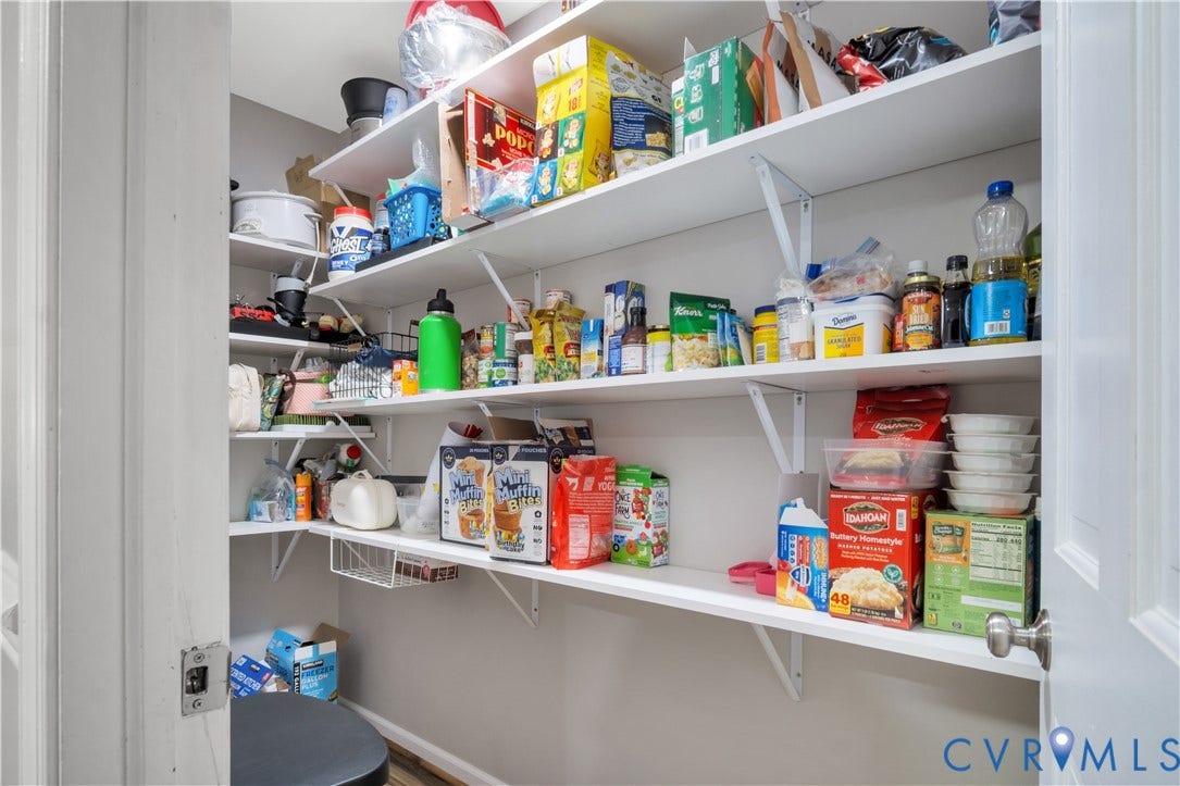 Pantry with multiple white shelves and integrated storage