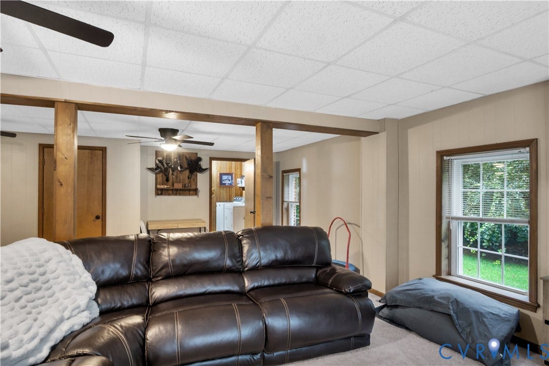Exposed wood beams, two ceiling fans, and a window with natural light