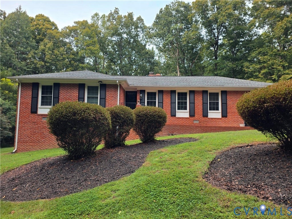 Brick exterior with dark shutters, established landscaping, and a well-maintained lawn