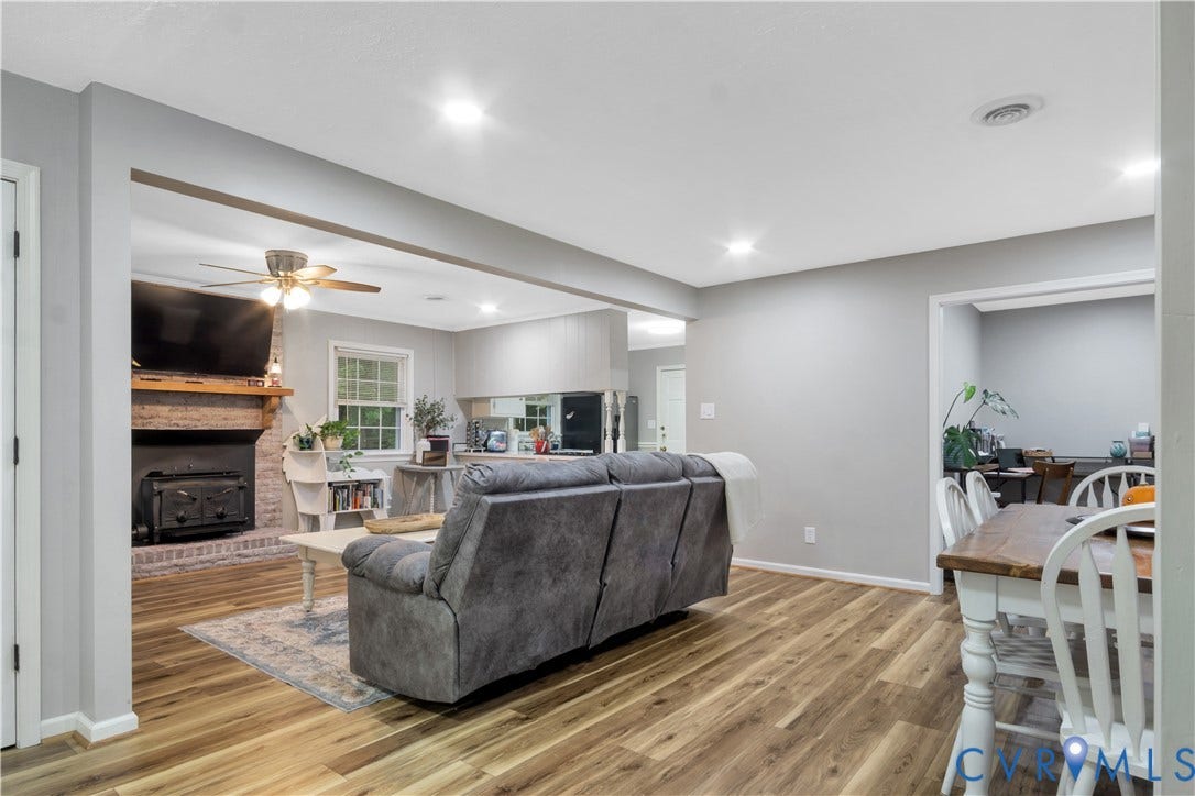 Open concept living space featuring wood-finish flooring, recessed lighting, and a brick fireplace