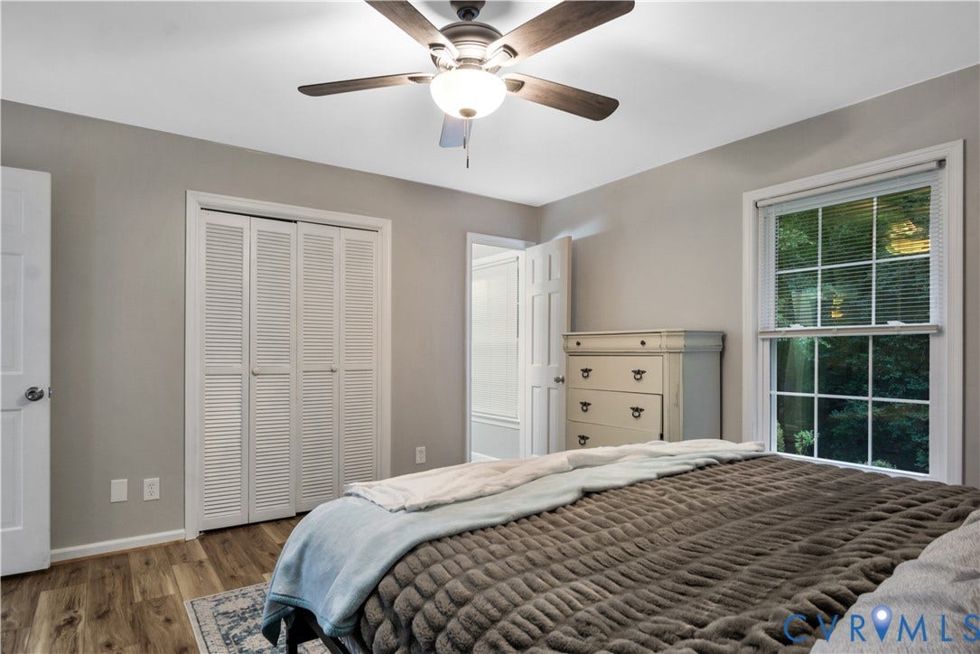 Wood-finish flooring, louvered bi-fold closet doors, and a ceiling fan with integrated lighting