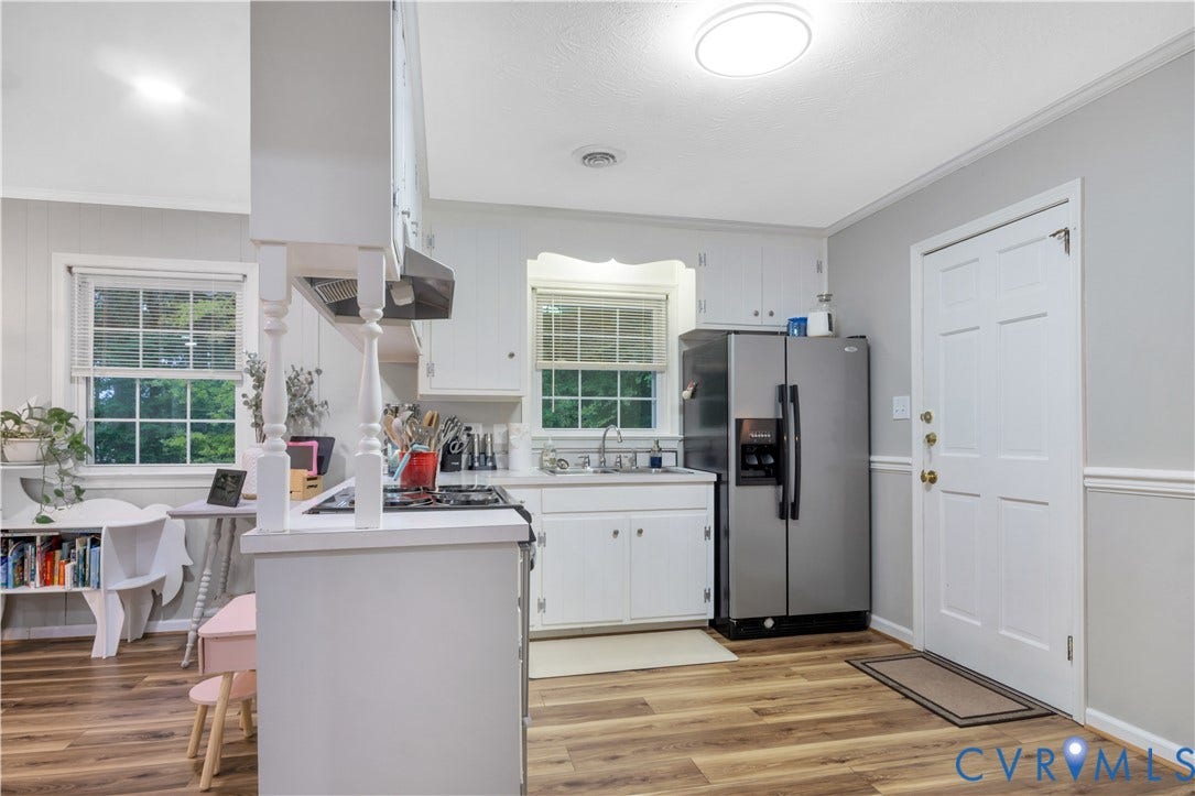 Kitchen featuring white cabinetry, light countertops, stainless steel appliances, wood-finish flooring, and natural light from multiple windows