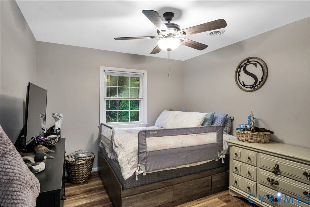 Recessed window with natural light, ceiling fan with integrated lighting, wood-finish flooring, light neutral wall paint