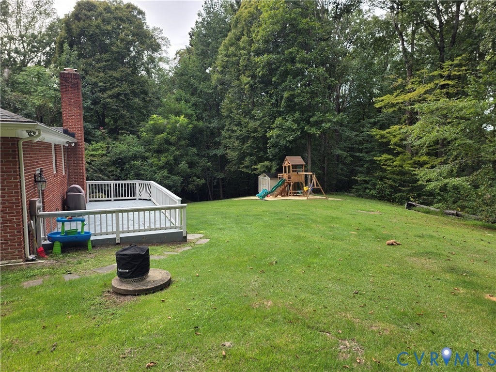 Expansive green lawn with mature trees and a rear deck featuring white railings