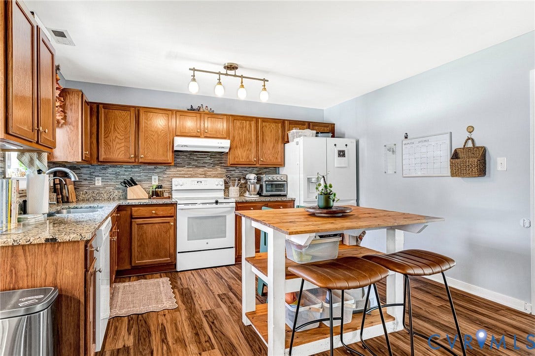 Kitchen featuring wood-finish flooring, wood cabinetry, stone countertops, and a tile backsplash