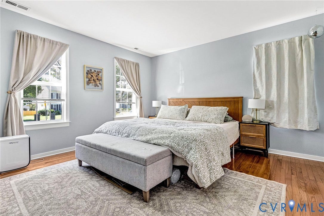 Hardwood flooring, wood-finish headboard, built-in closet with shelving, and window with drapes