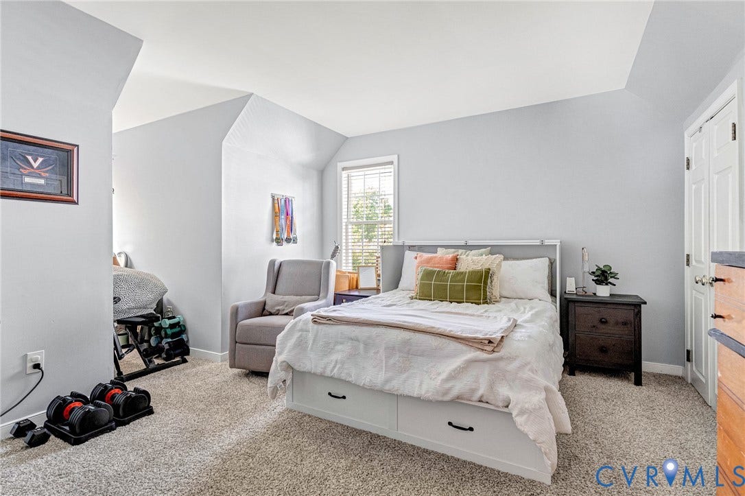 Carpeted flooring, vaulted ceiling, built-in storage drawers, a window with blinds, and a paneled door