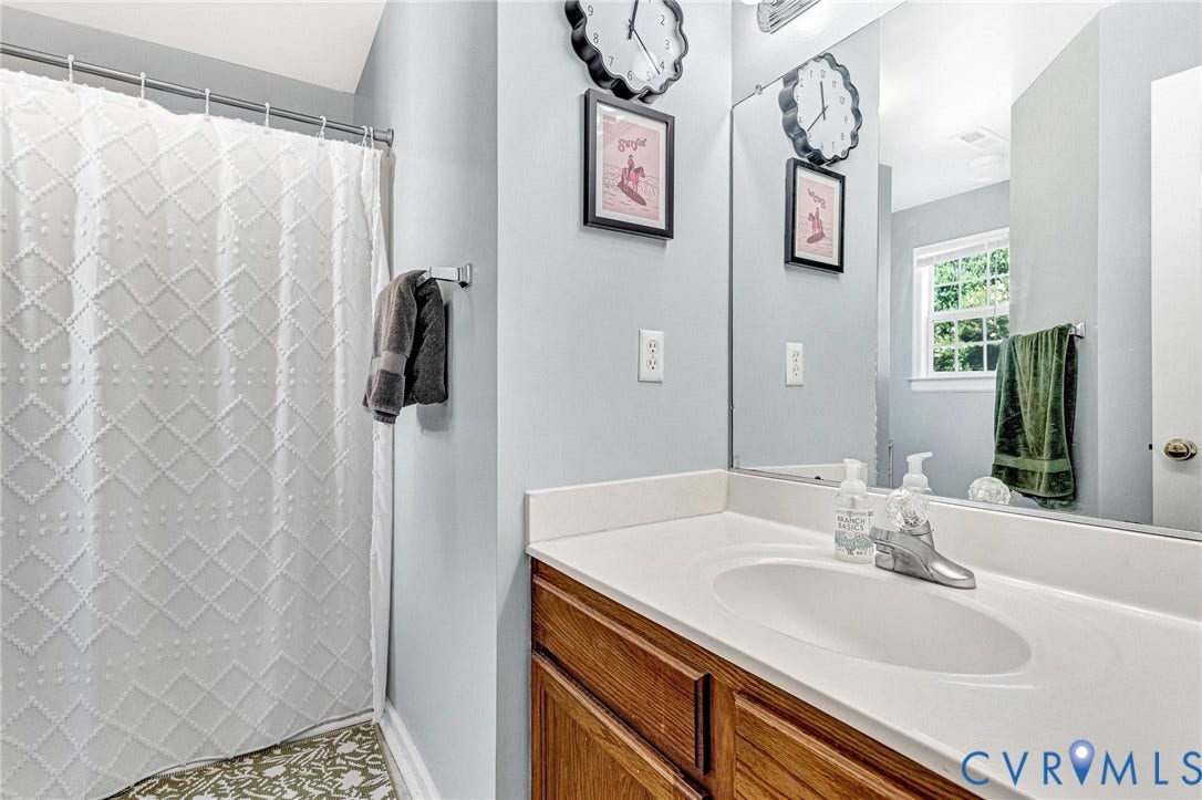 Single vanity with a light countertop, integrated sink, and wood-finish cabinetry